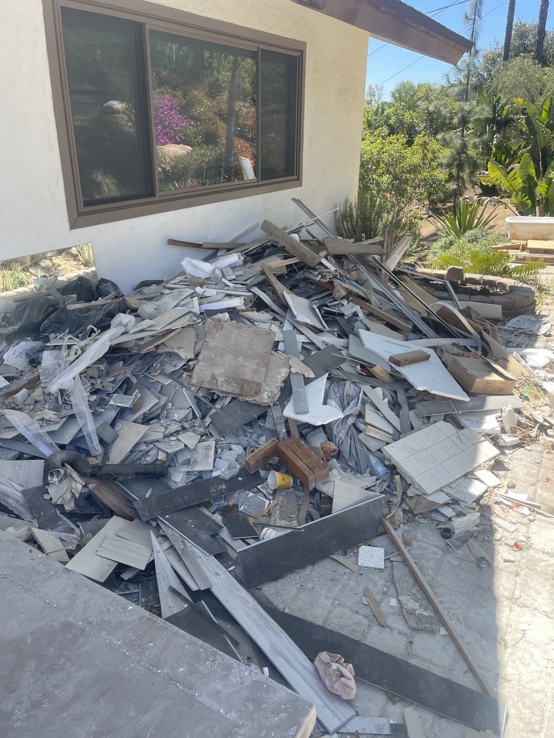 Backyard of a home full of demolished junk including concrete, stone, and wood